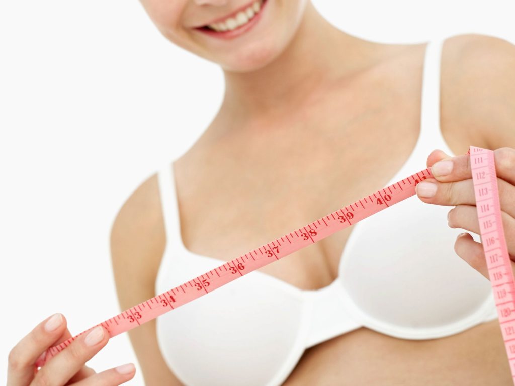woman holding a measuring tape before measuring her bra