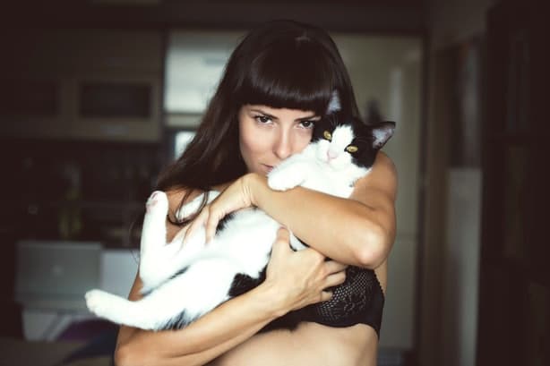 woman in a bra holding her cat